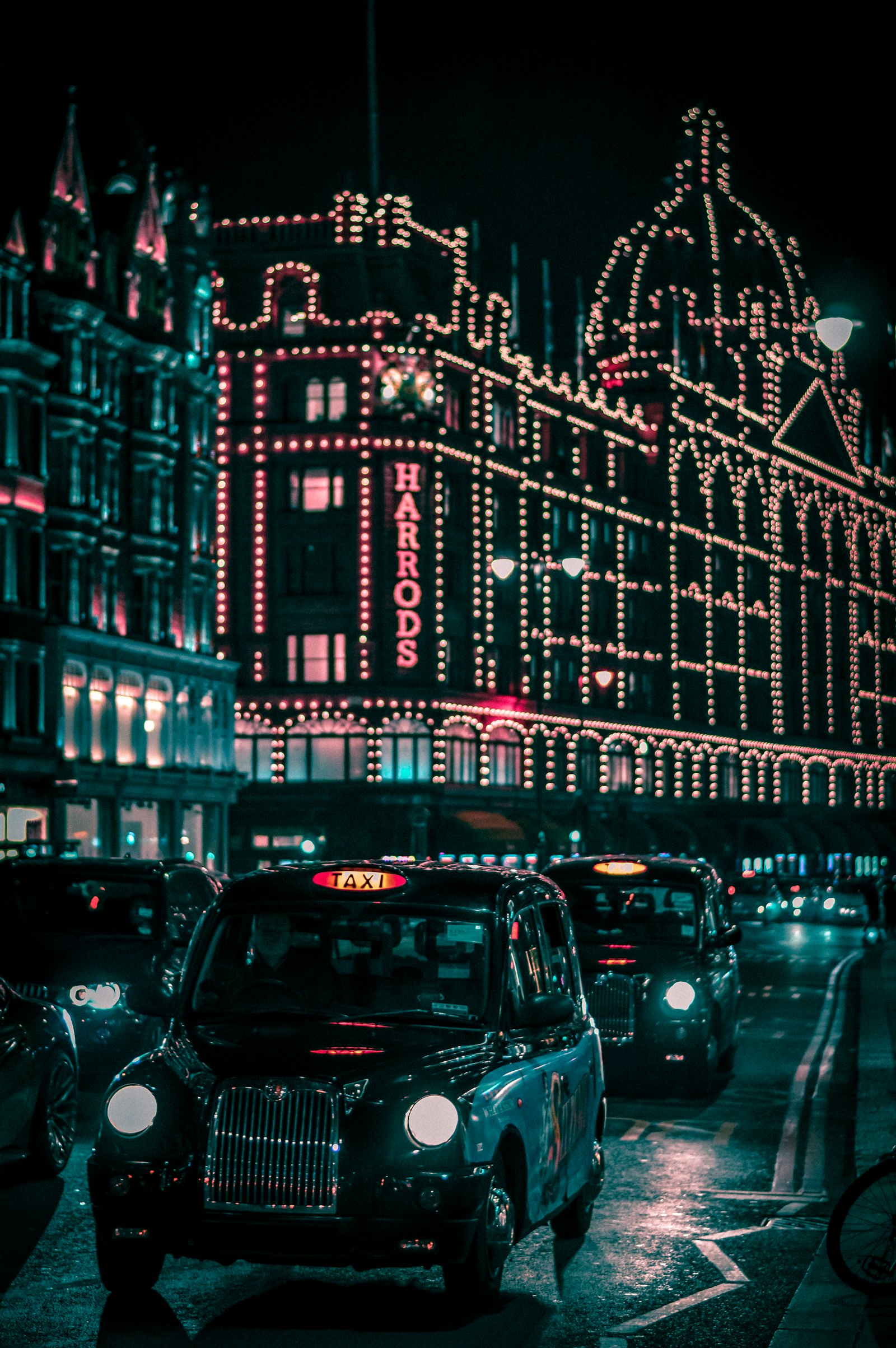 Black cab on a London street at night lit by shop lights