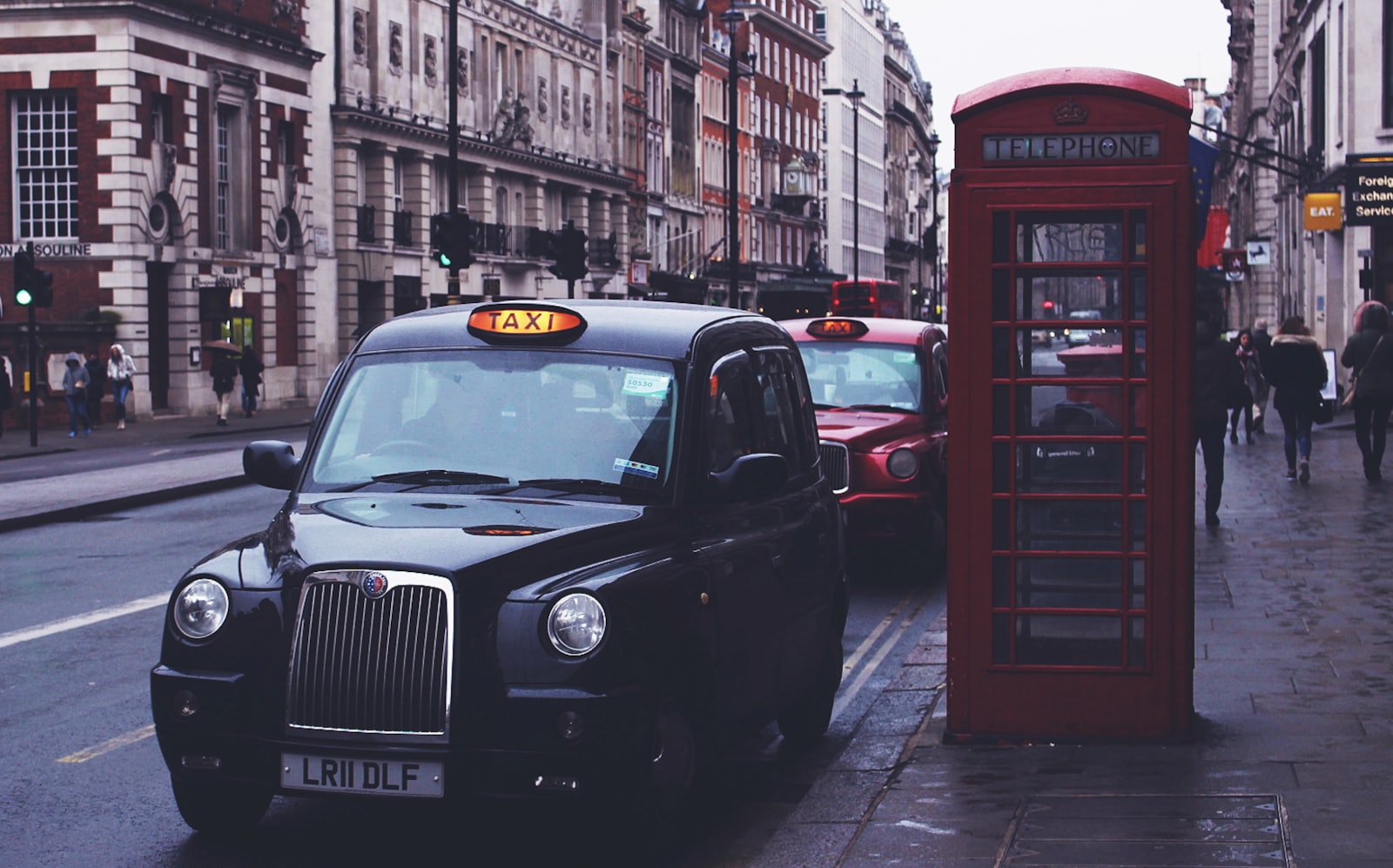 Black hackney carriage taxi beside a red British telephone box